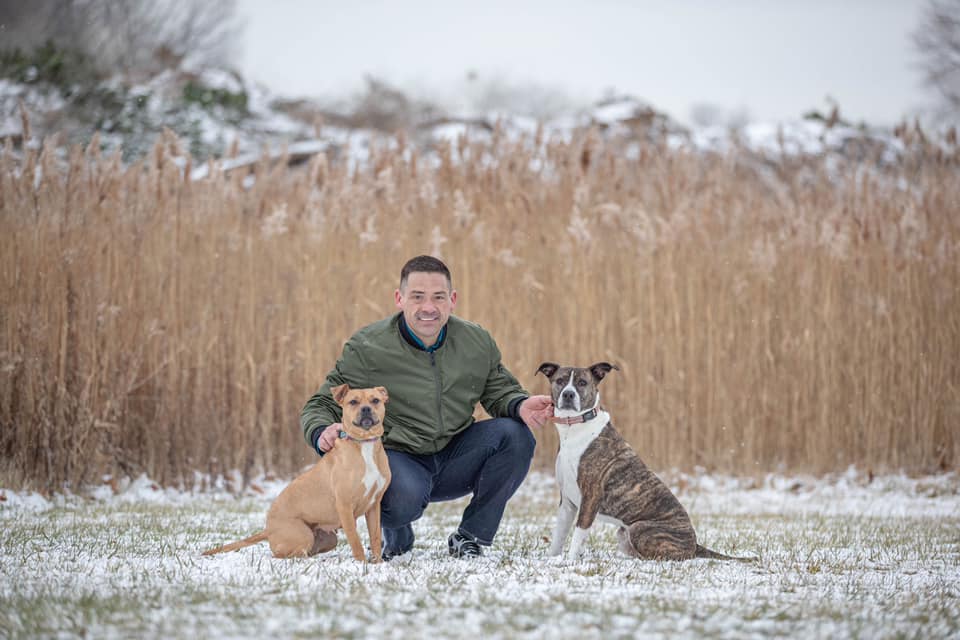 man posing with two dogs