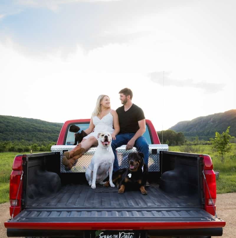 smiling couple with their dogs in a car trailer