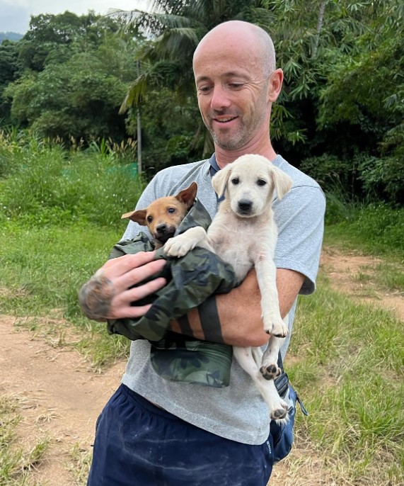 a man holds two rescued dogs from the forest in his arms