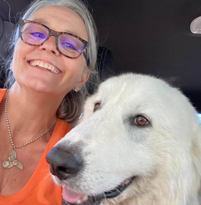a white dog takes a picture with a smiling woman