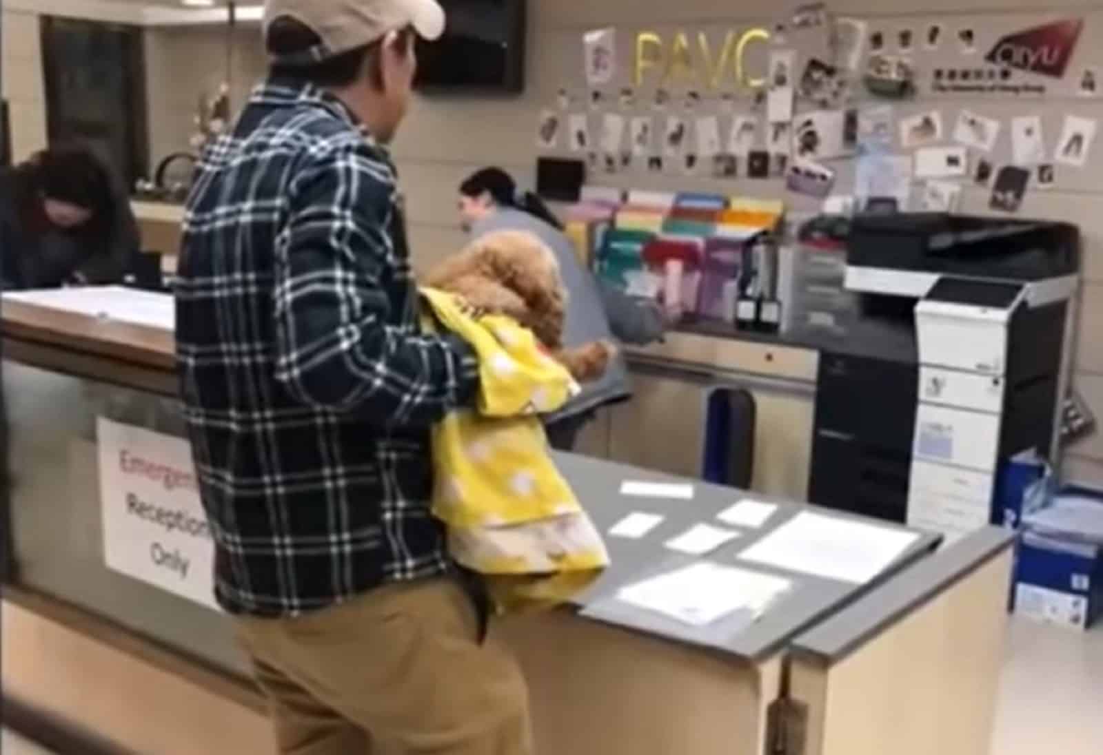 man holding injured puppy at vet clinic