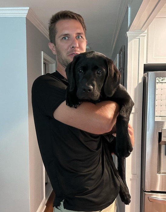 a man holds a confused dog in his arms