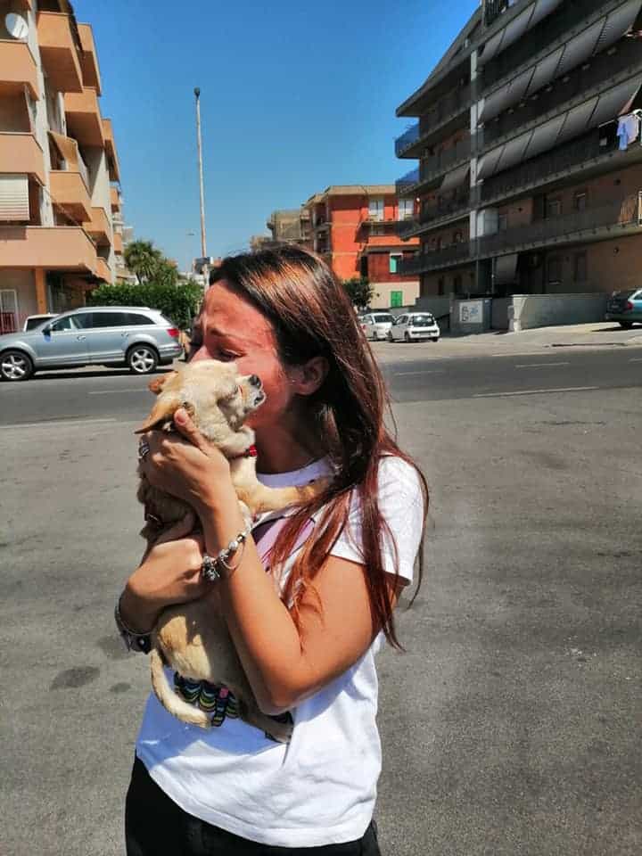 woman holding and hugging her dog on the street