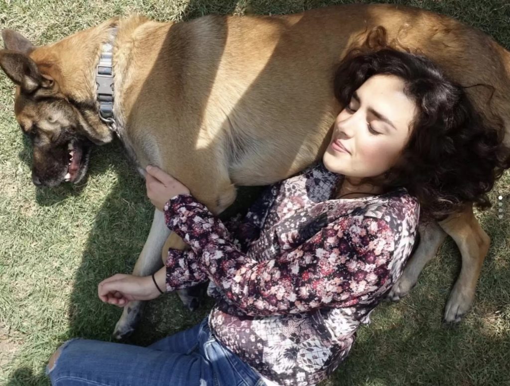 a beautiful girl lies with her head resting on her dog