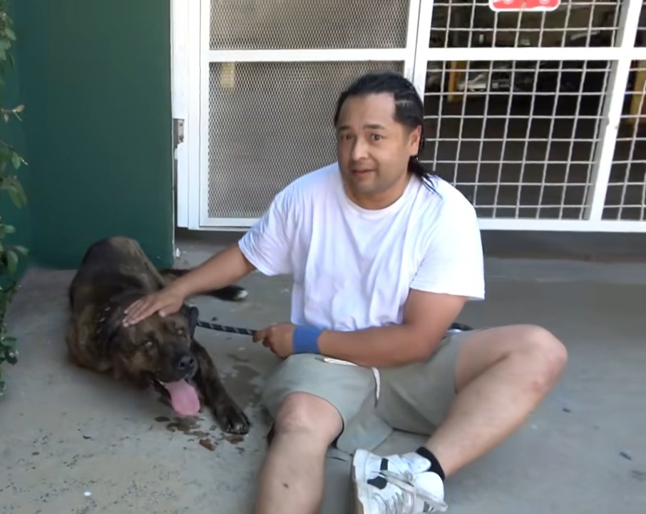 man and sitting and petting the dog
